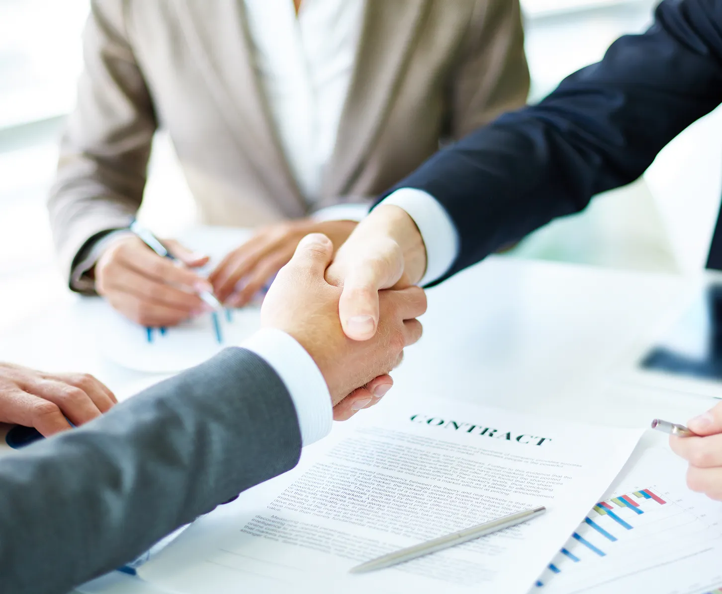 Deux personnes se serrent la main sur une table avec un contrat et des notes.